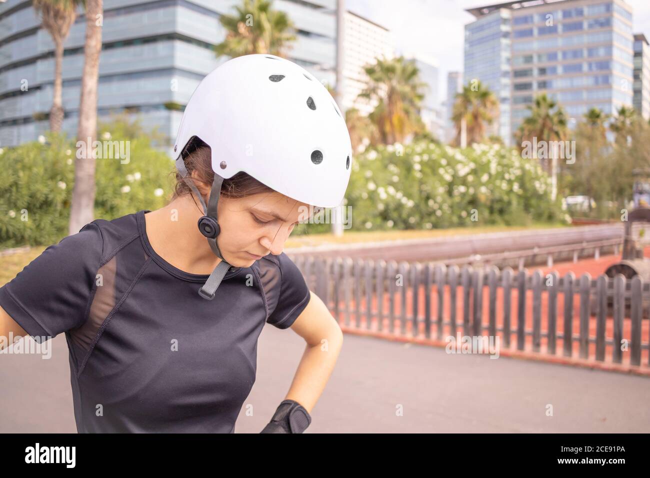 Very sad after failure young roller skater caucasian woman in the white helmet and black sporty clothes, skatepark, urban environment. Stock Photo