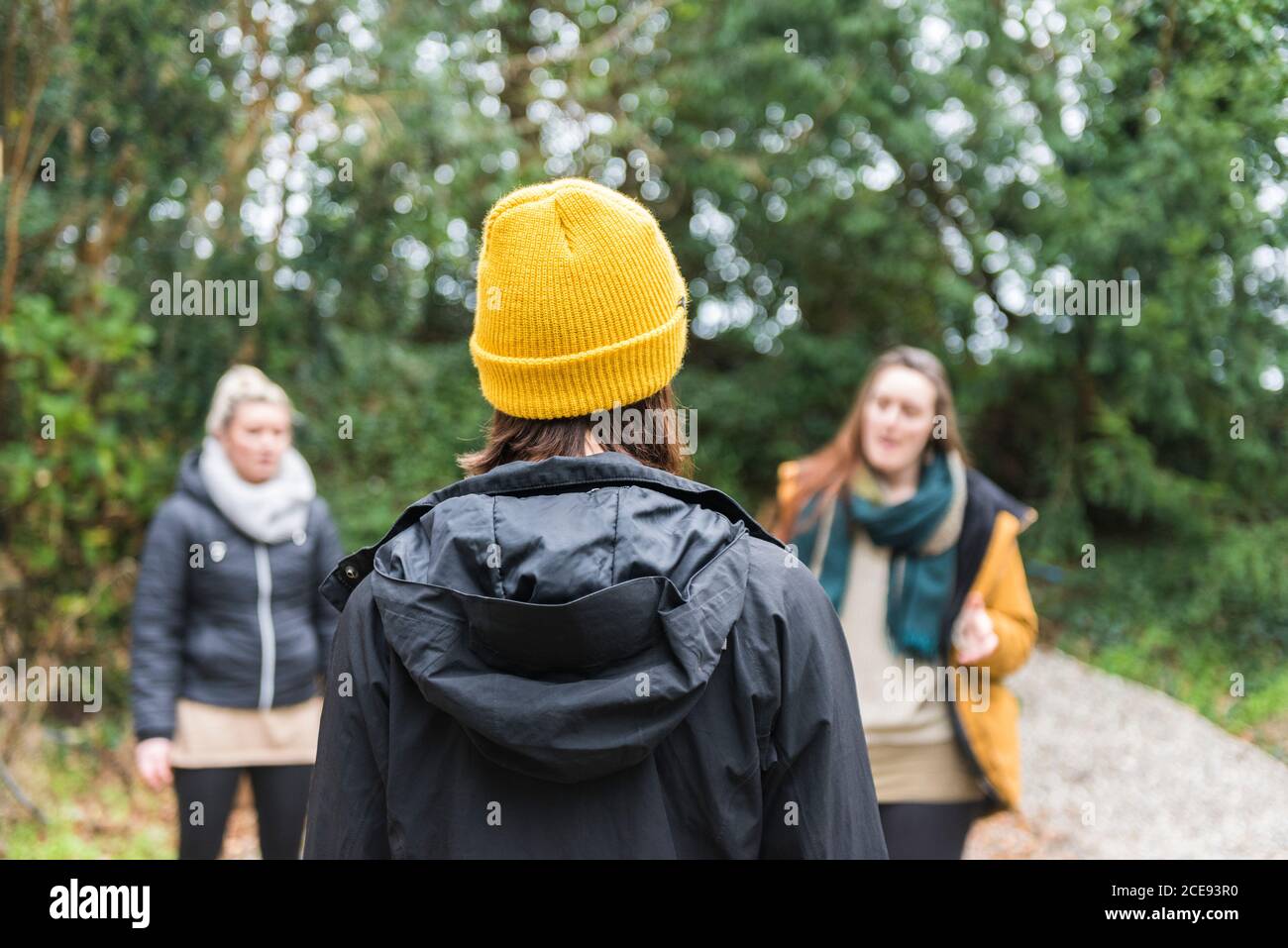 A rear view of a woman wearing a bright vibrant yellow knitted hat in cold weather meeting her friends. Stock Photo