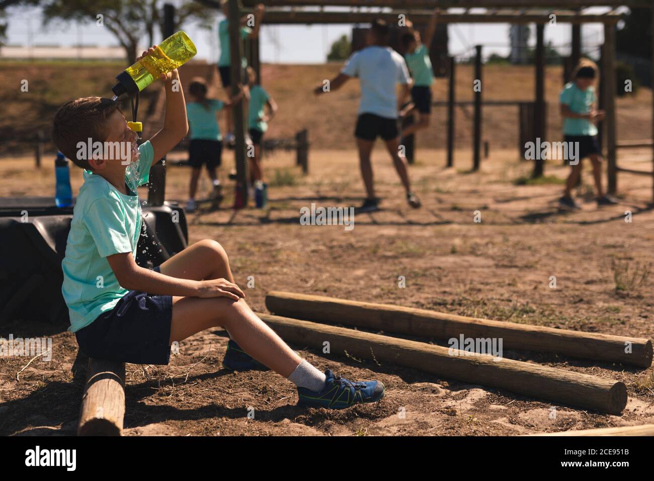 Boy pouring water on his face from a bottle at a boot camp Stock Photo