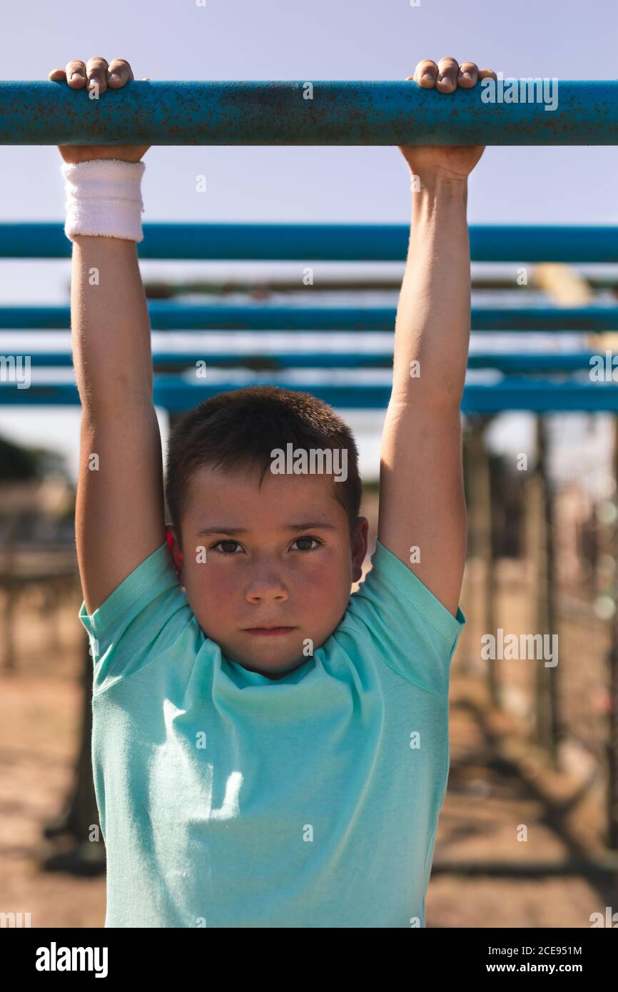 Portrait of boy hanging on monkey bars at a boot camp Stock Photo