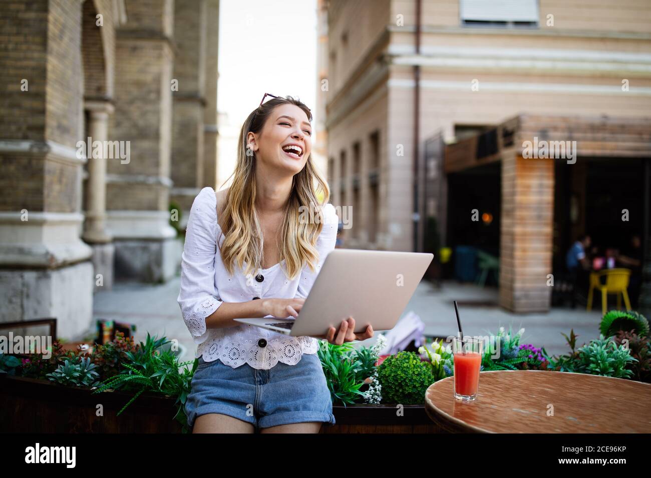 Happy excited woman reading good news on line in a laptop outdoor Stock Photo
