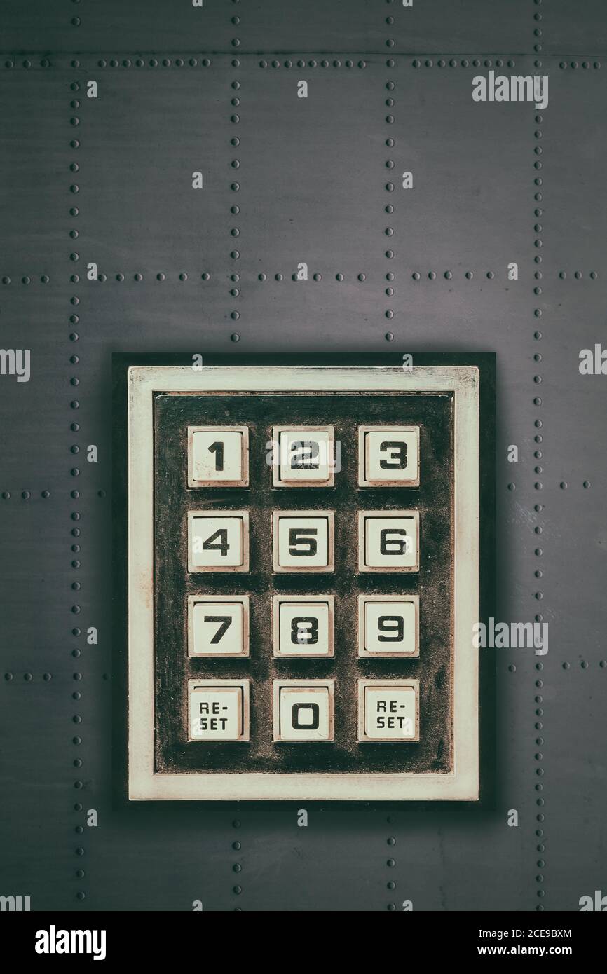 Vintage weathered keypad with reset and number buttons on a dark grey wall Stock Photo