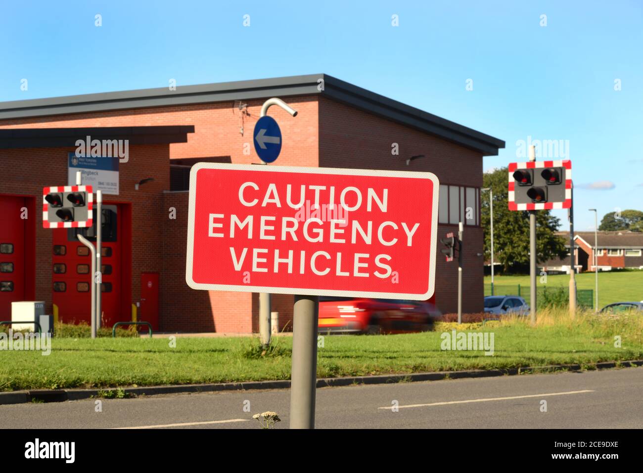 caution emergency vehicles warning sign and lights outside fire station leeds united kingdom Stock Photo