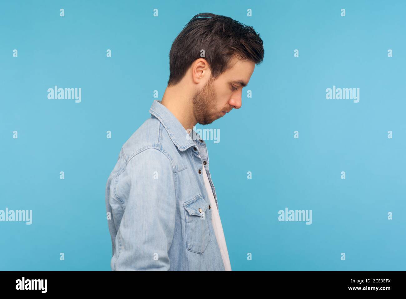 Profile view of sad young man looking down Stock Photo - Alamy