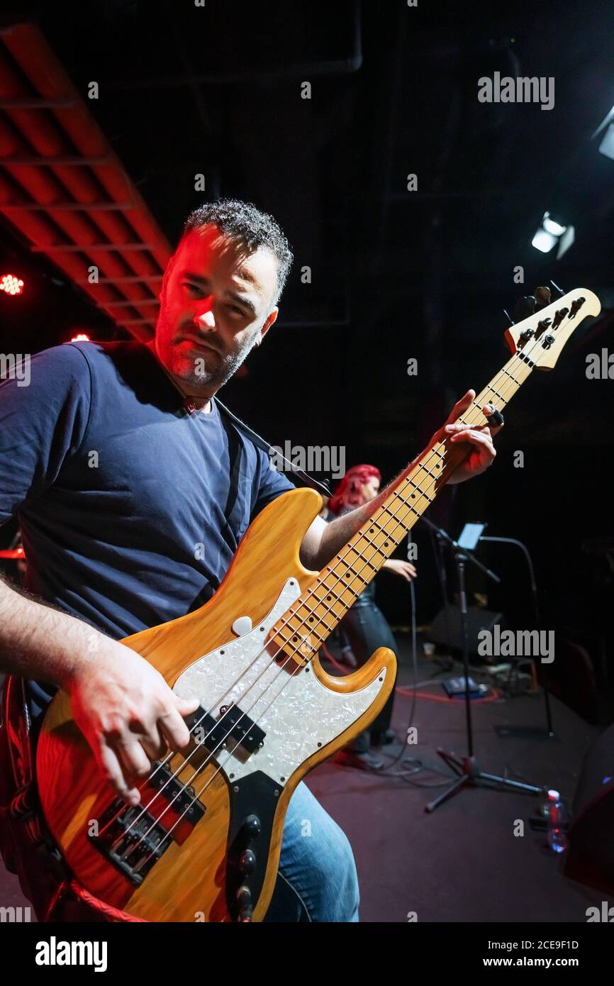 Caucasian Man is Performing on the Stage with Band. Handsome Male Person is Playing on Bass Guitar at Concert. Stock Photo