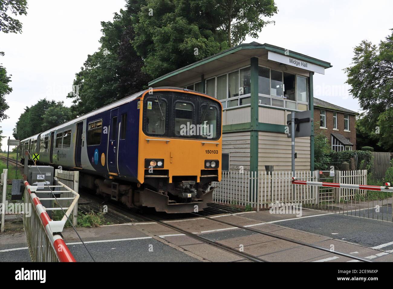 A Northern train crosses the level crossing at Midge Hall, near Leyland in Lancashire where there is the possibility of the station reopening Stock Photo