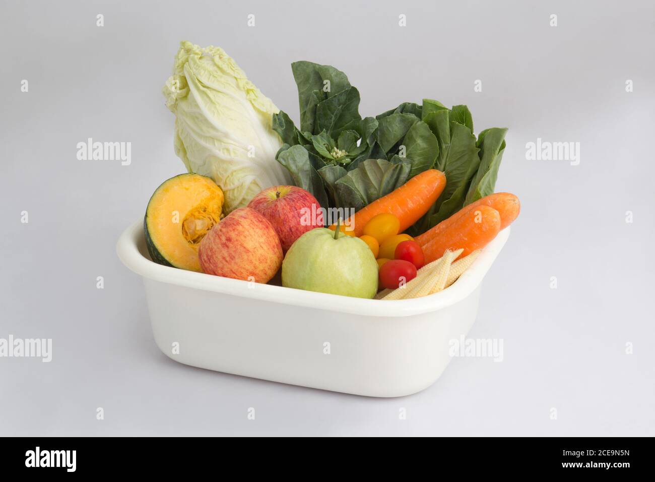 vegetables and fruits in white plastic bowl isolated on white background Stock Photo