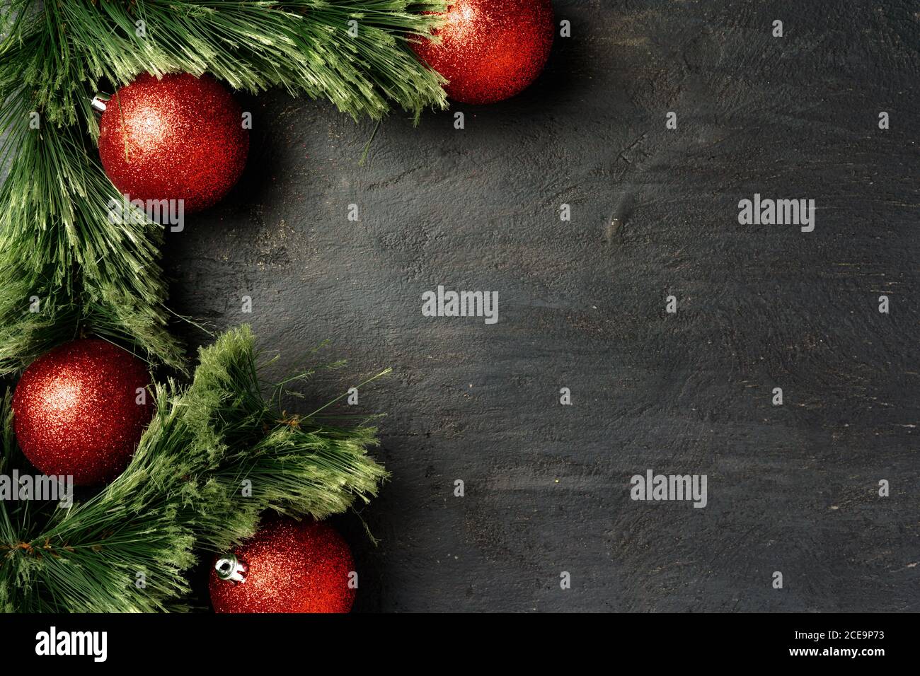 Christmas background with fir tree branches and red baubles on black ...