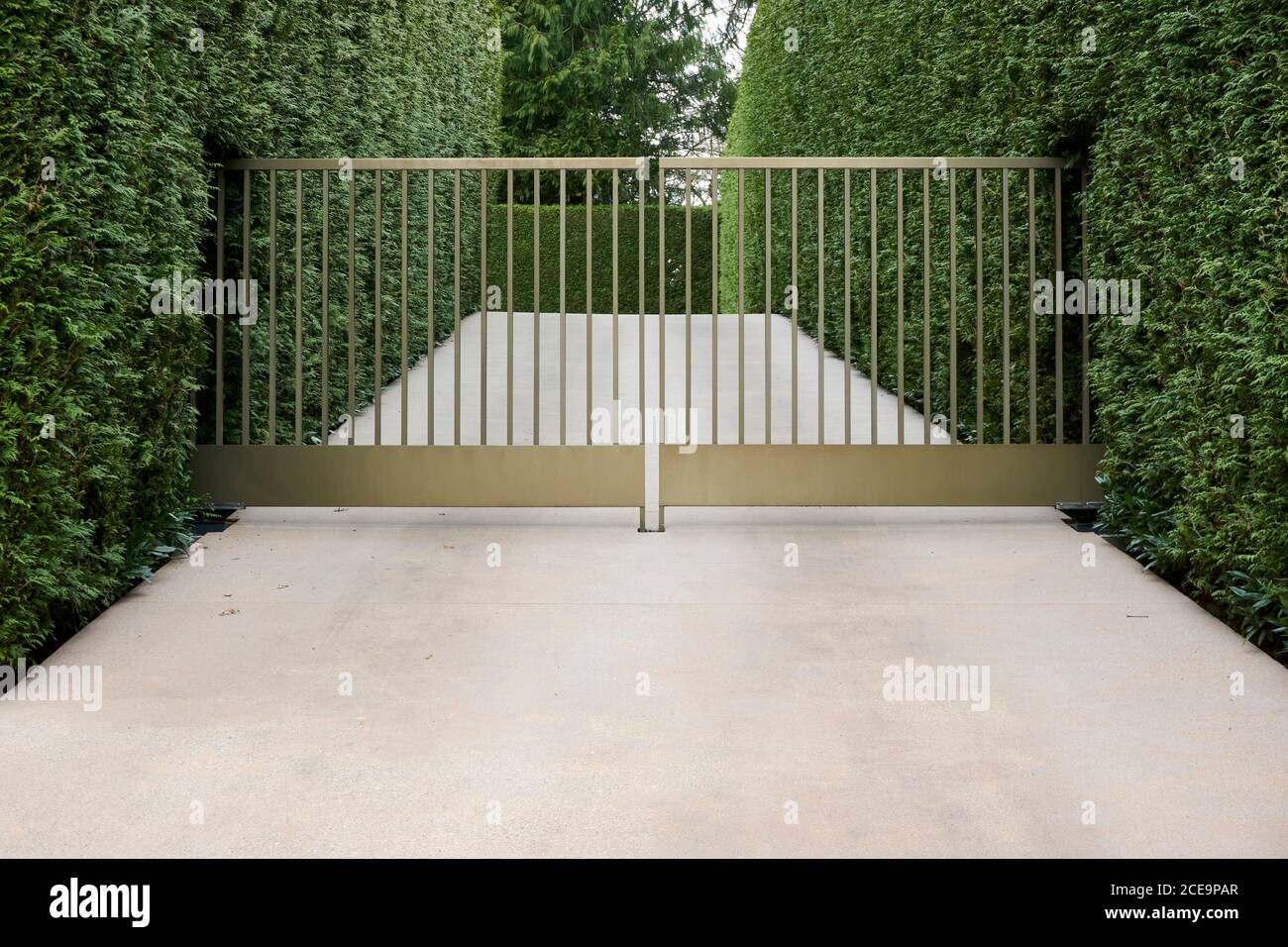 Concrete driveway with locked metal gate in a residential neighbourhood Stock Photo