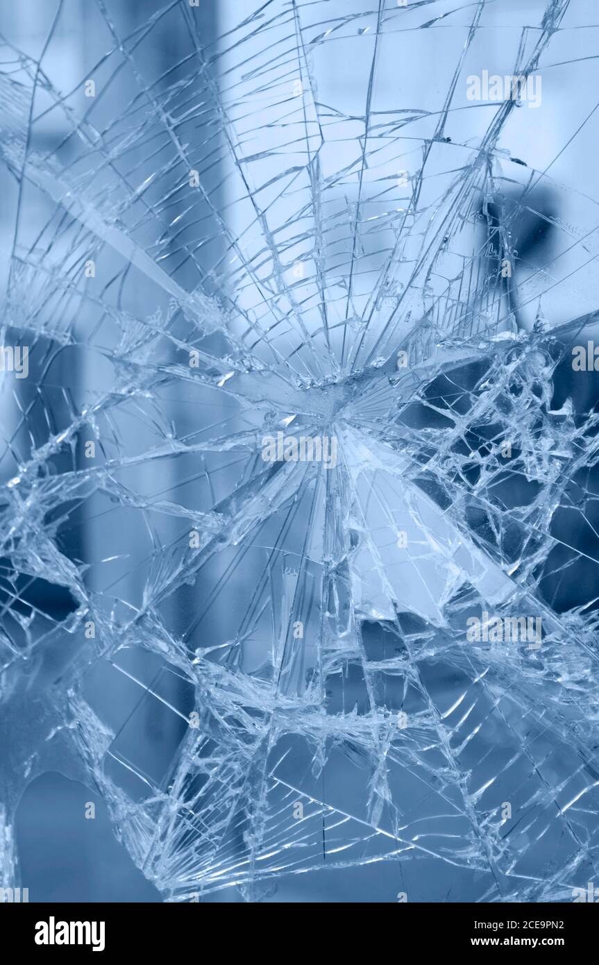 Accident - close-up of broken window. Detail of rifts of cracked glass. Blue background. Stock Photo
