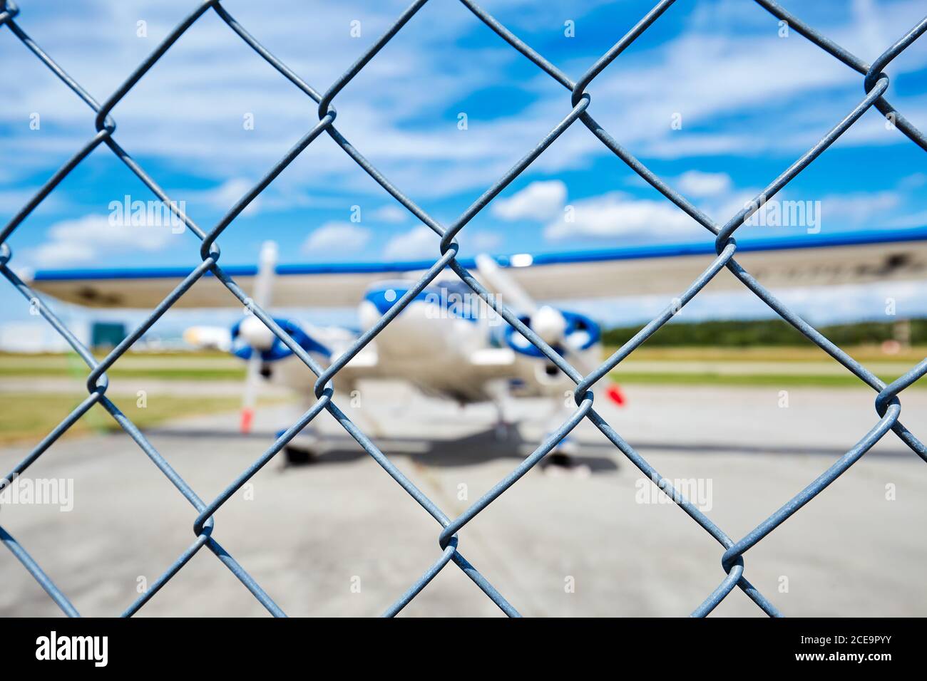 Aircraft on runway behind wire mesh fence Stock Photo