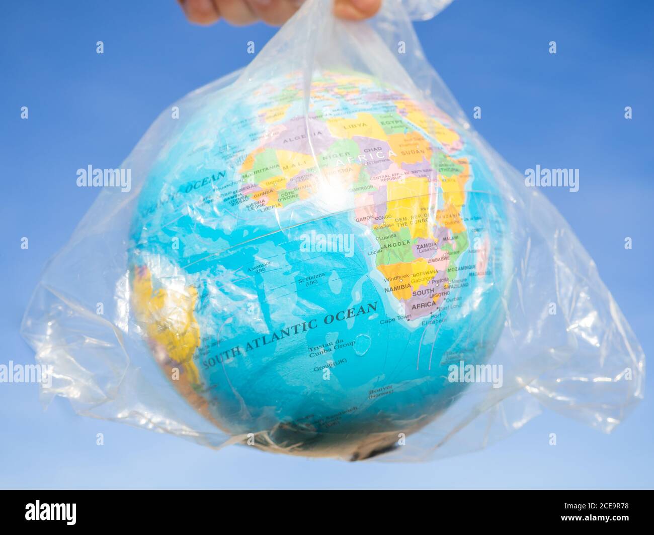 A person with a terrestrial globe or planet Earth in his hands inside a plastic bag. Ecology concept Stock Photo