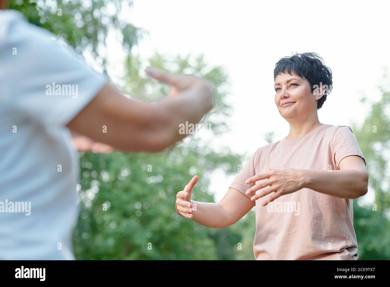 Content attractive brunette coach moving arms with student while developing imagination at qigong practice Stock Photo