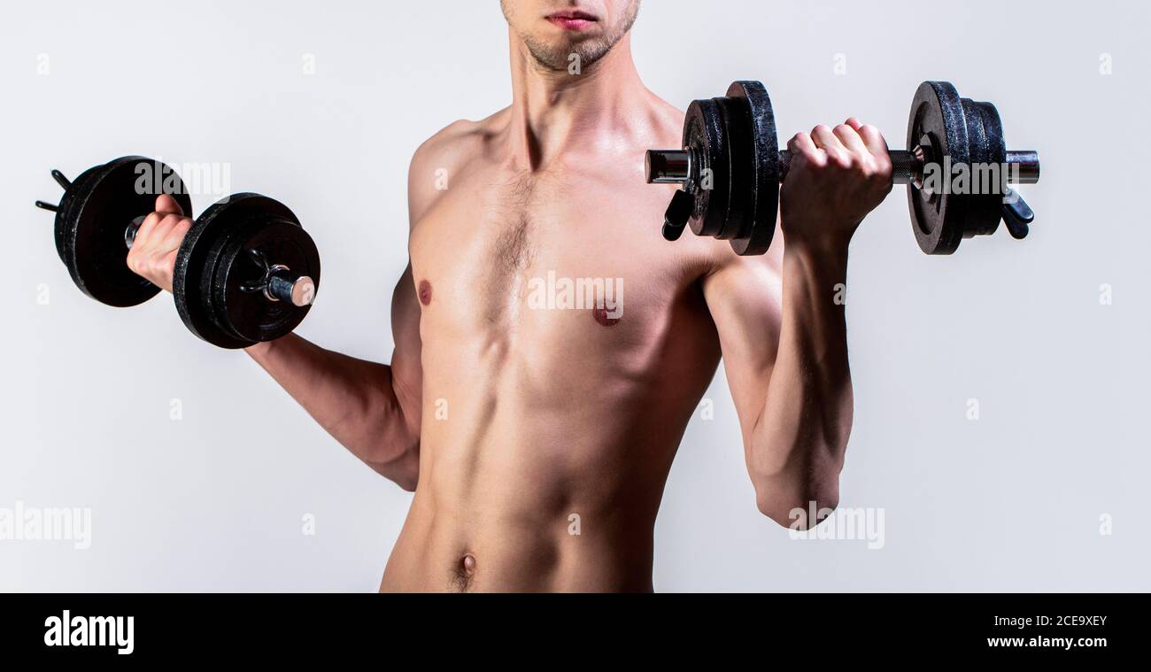 Man holding dumbbell in hand. Skinny guy hold dumbbells up in hands. A