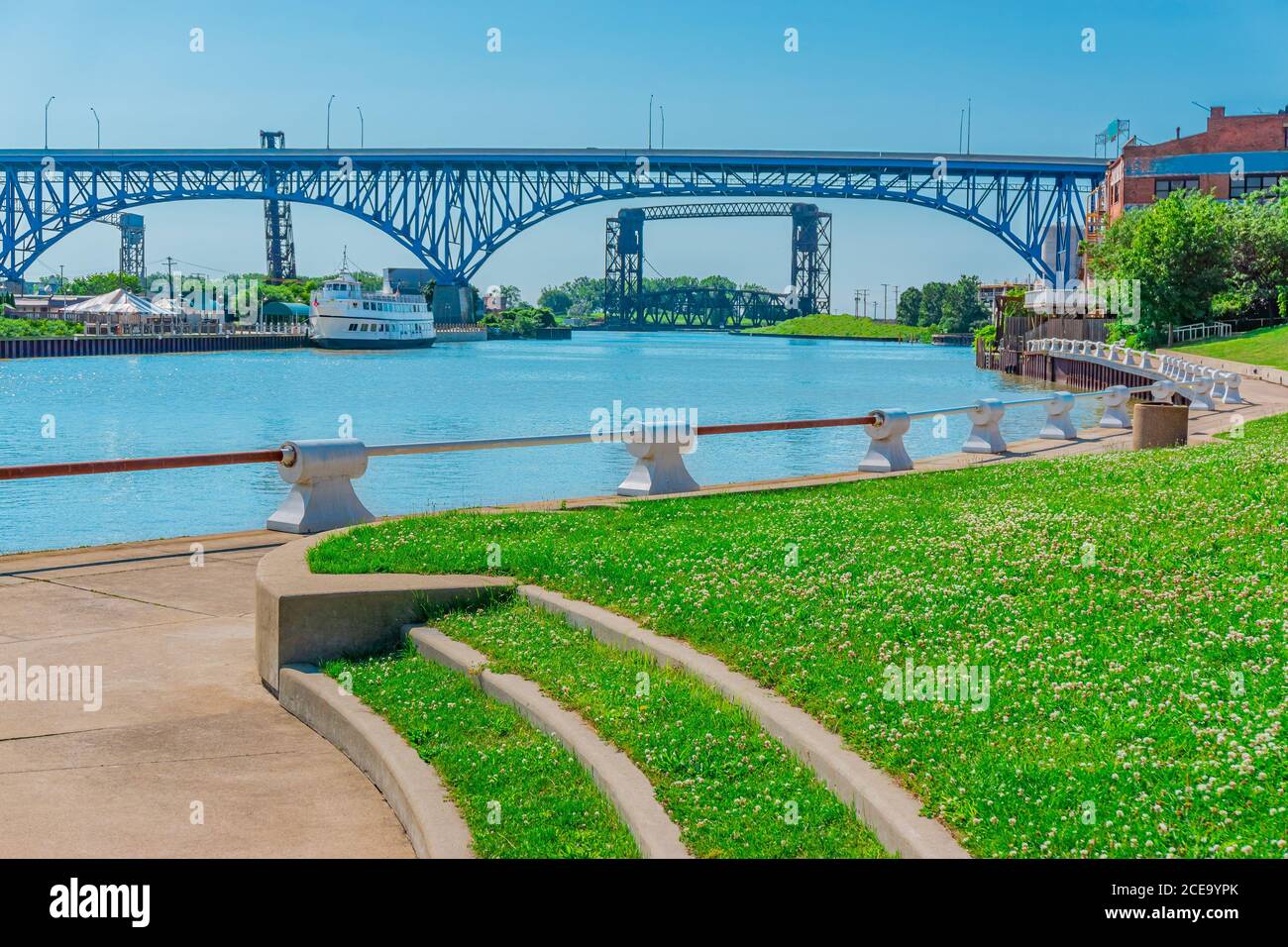 Cuyahoga River runs under a bridge and through the town of Cleveland, Ohio. Older structures line the river, as well as contemporary. Stock Photo