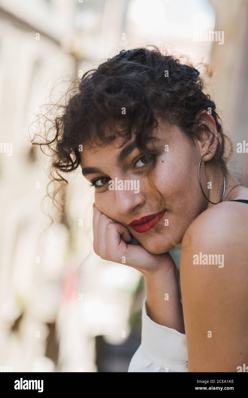 Close-up of charming curly girl in earrings and with red lips laughing happily and looking at camera Stock Photo