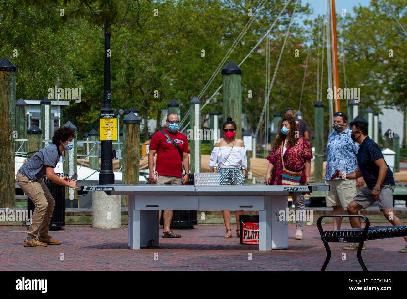 Annapolis, MD 08/21/2020: Two men are playing ping pong (table tennis) in the park area near Annapolis Marina. They have spectators watching the game. Stock Photo