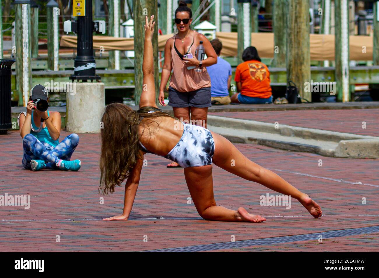 Annapolis, MD 08/21/2020: A teen gymnast girl in swimsuit  is posing to a professional photographer on cobblestone ground of Annapolis Marina  Mother Stock Photo