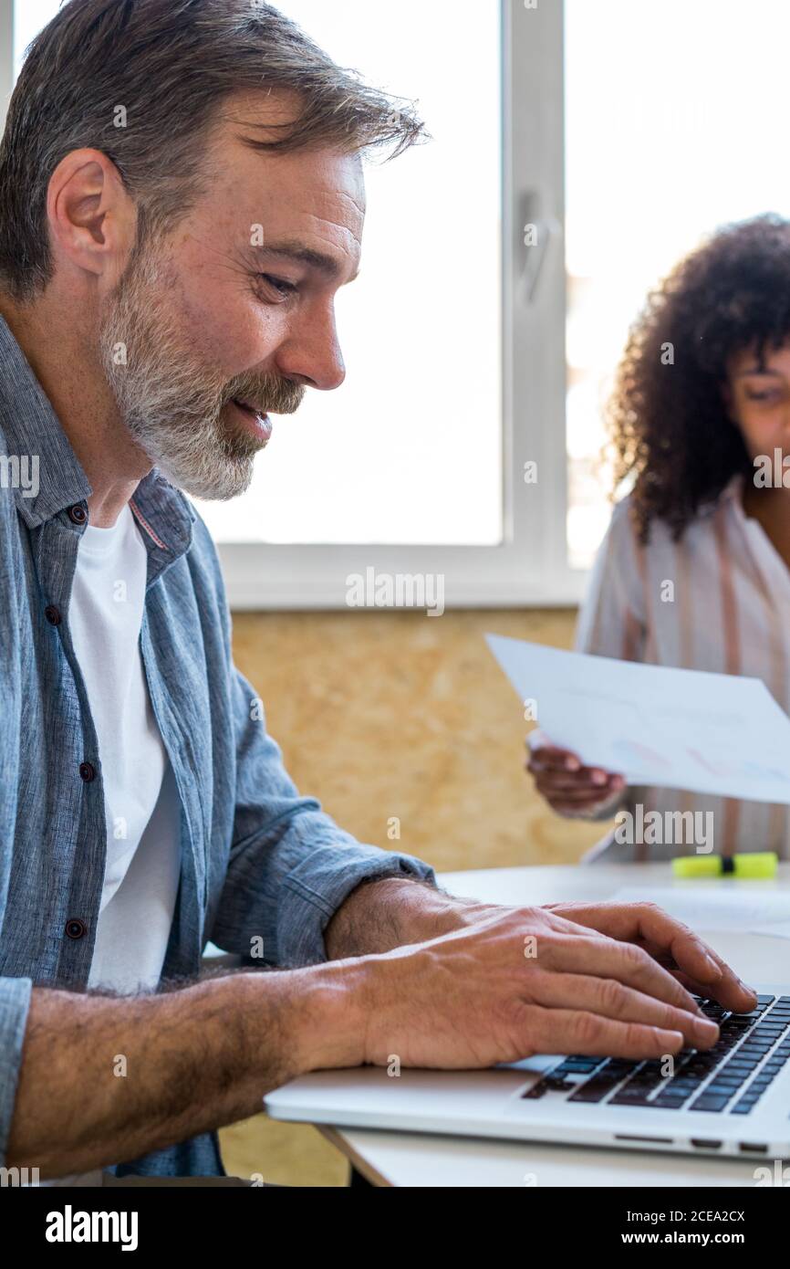 man using laptop near chatting colleagues Stock Photo