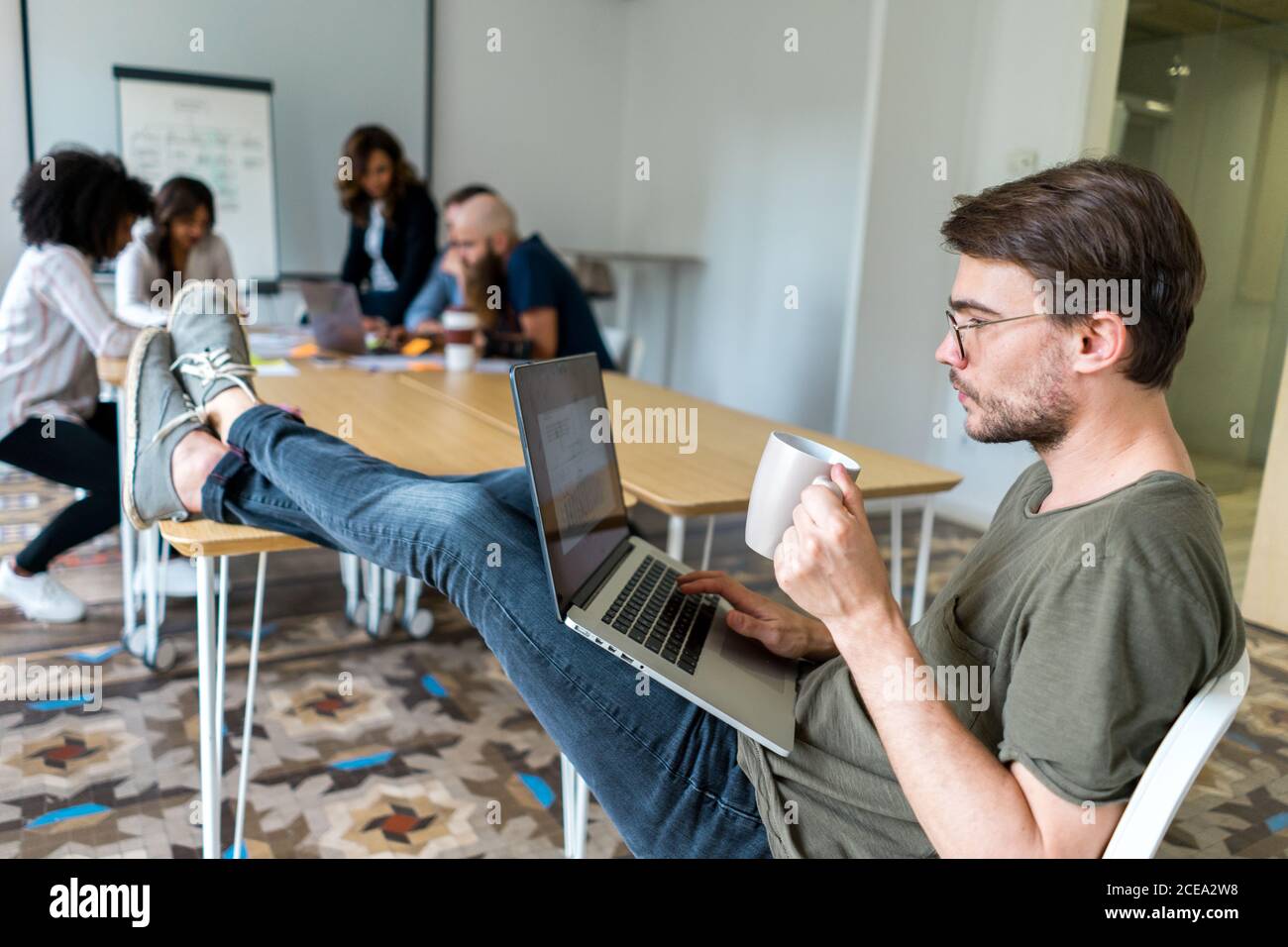 Young man sitting in office with laptop Stock Photo