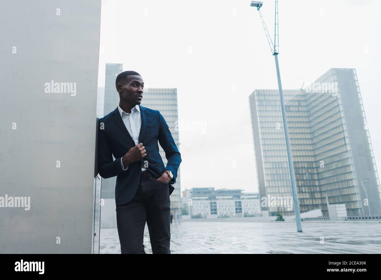 African-American businessman leaning on wall outdoors Stock Photo