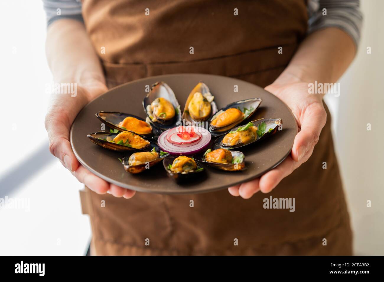 unrecognizable female holding ceramic plate with portion of palatable boiled ussels Stock Photo