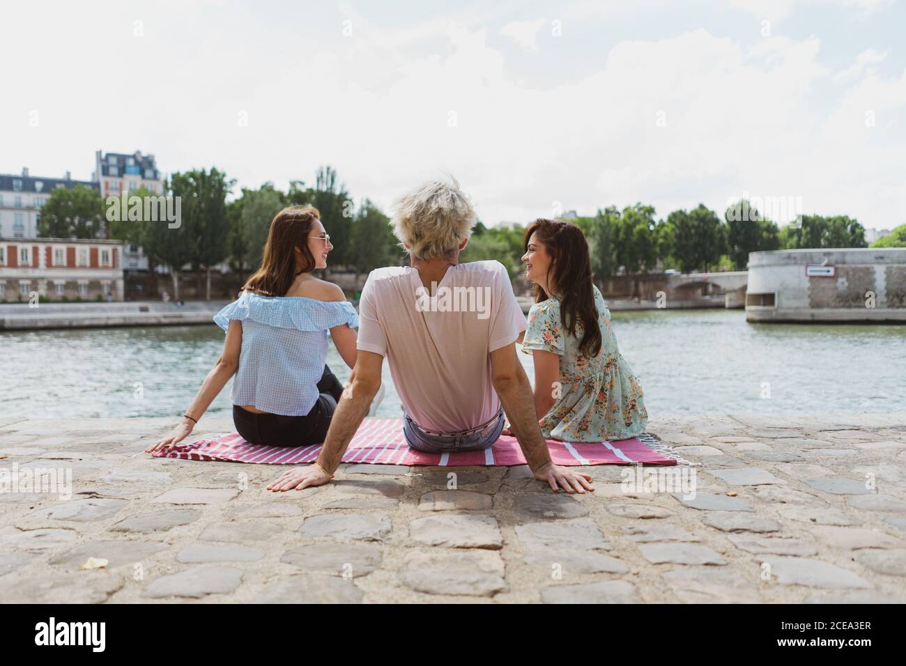 Friends sitting together on waterfront Stock Photo