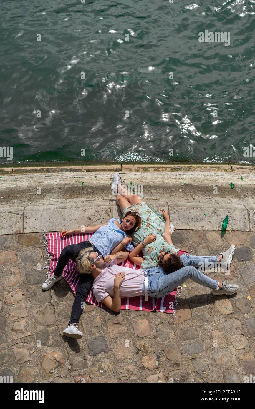 Friends lying on blanket on waterfront Stock Photo