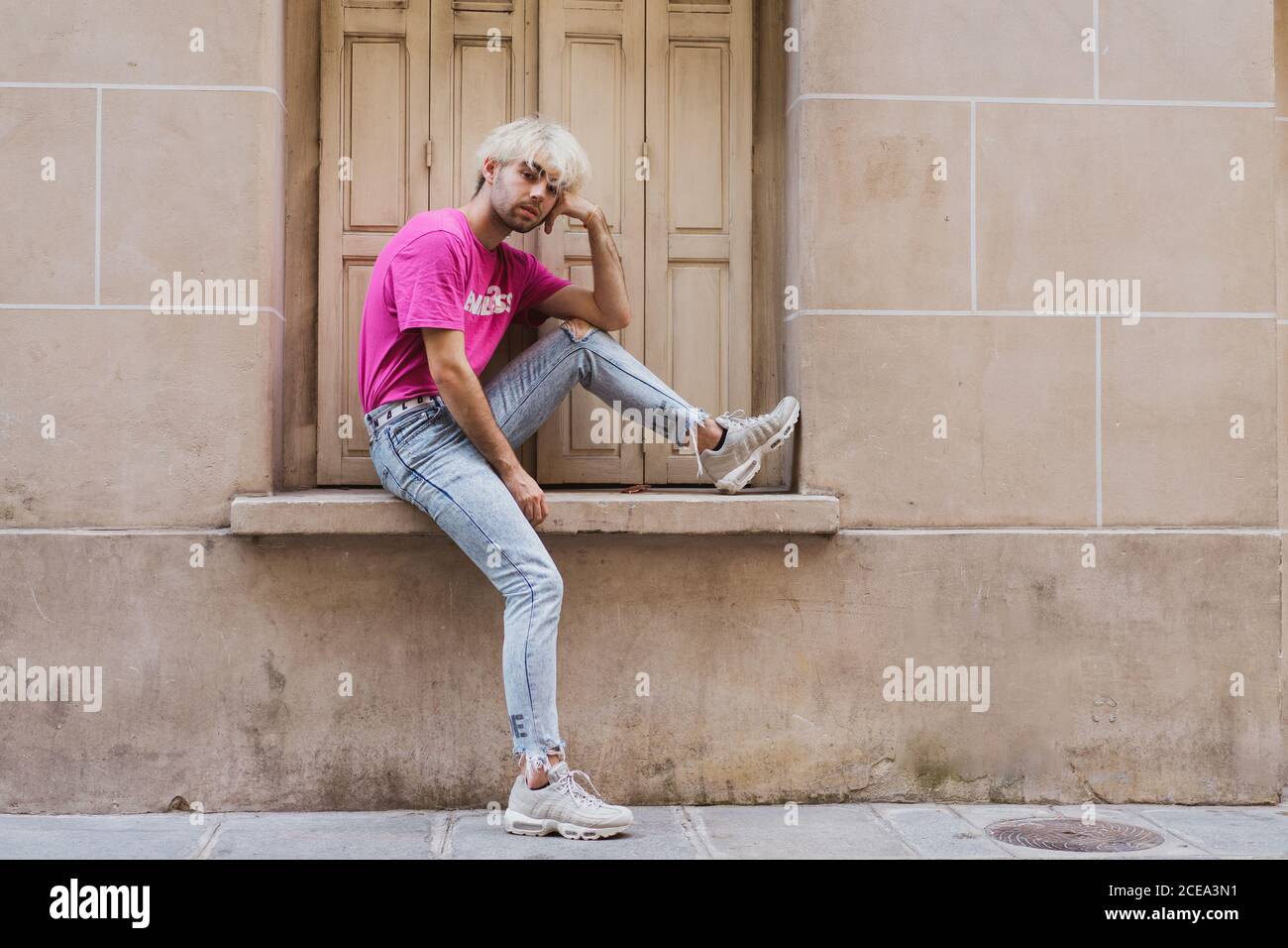Stylish man sitting on window sill Stock Photo