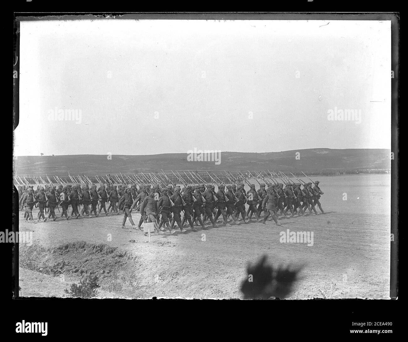 Ottoman infantry in formation parading on a field. The soldiers are marching with rifles shouldered. The weapons are Mauser model M1903 with bayonets fixed. The officers wear wool caps and leather boots, the soldiers headwraps and puttees. Photograph on dry glass plate from the Herry W. Schaefer collection, around 1913. Stock Photo