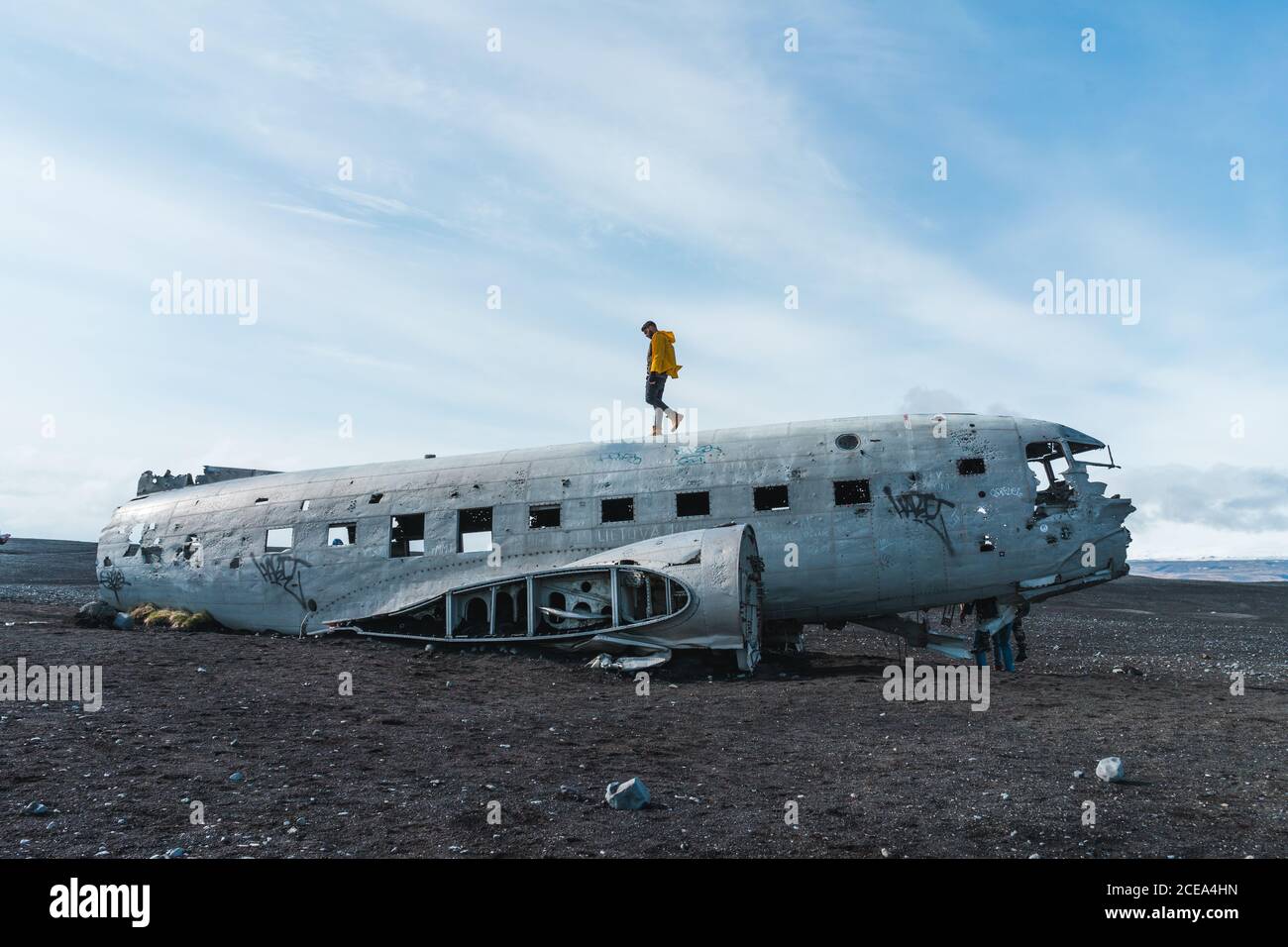 young man walking on carcass of abandoned aircraft while traveling through Iceland Stock Photo