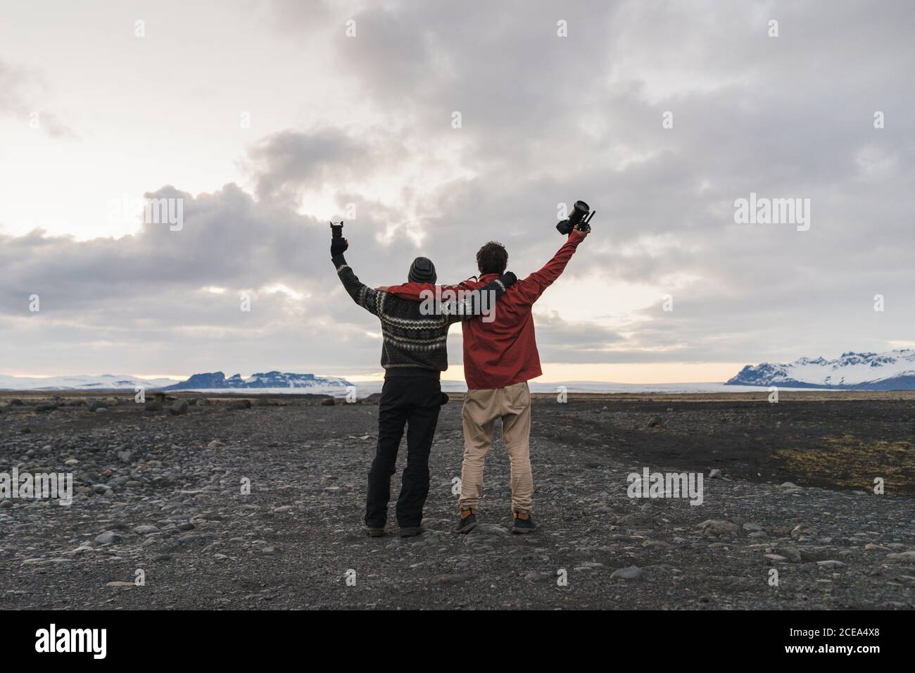 Smiling bearded friends standing in Iceland valley keeping camera over ...