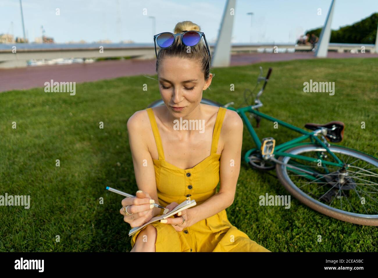Woman sitting on grass with bicycle Stock Photo