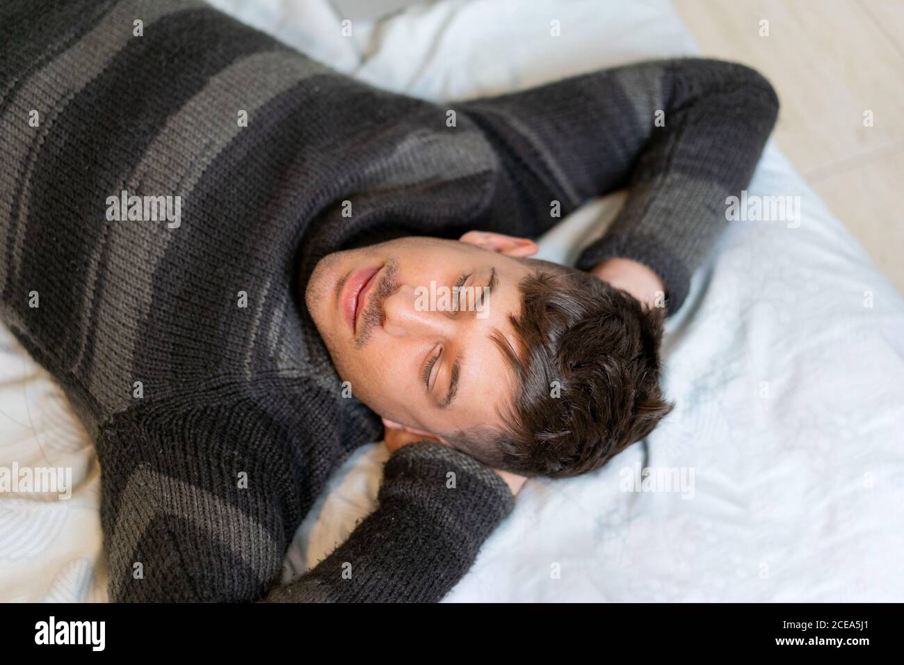 Smiling handsome man lying on bed Stock Photo