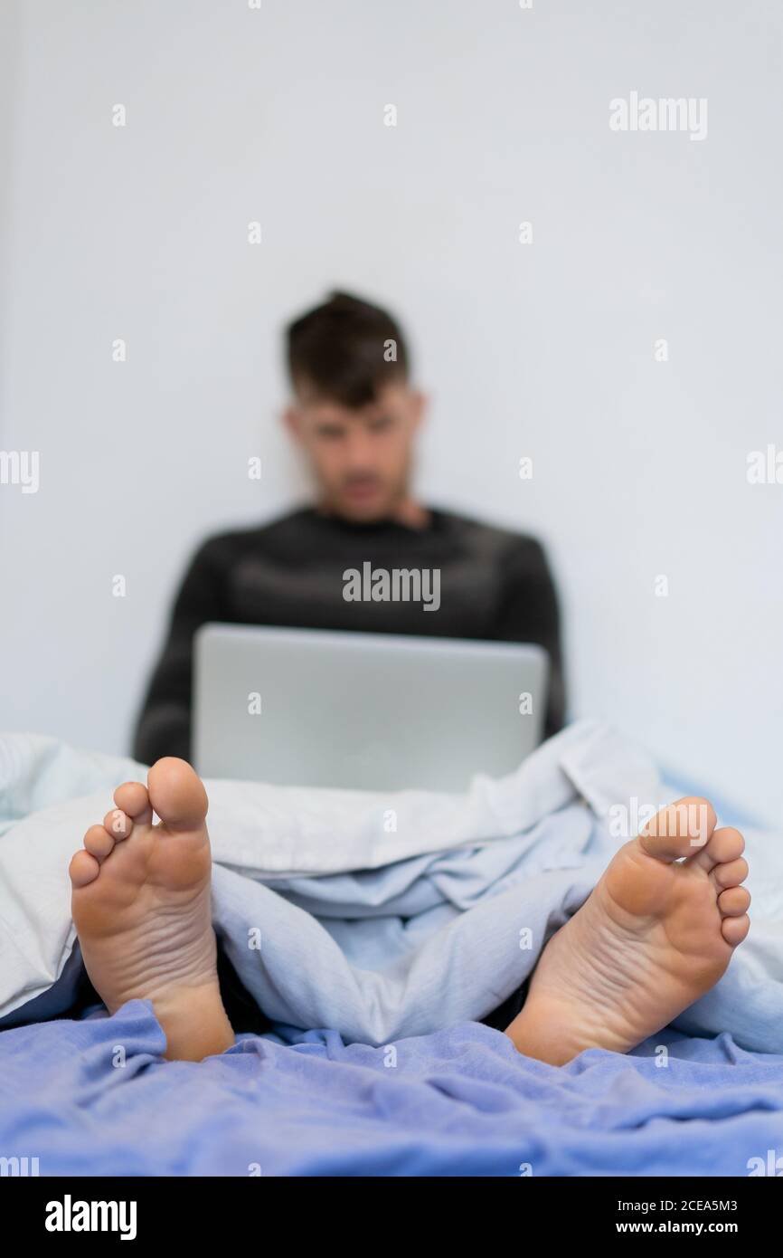 Barefoot man under blanket with laptop Stock Photo Alamy