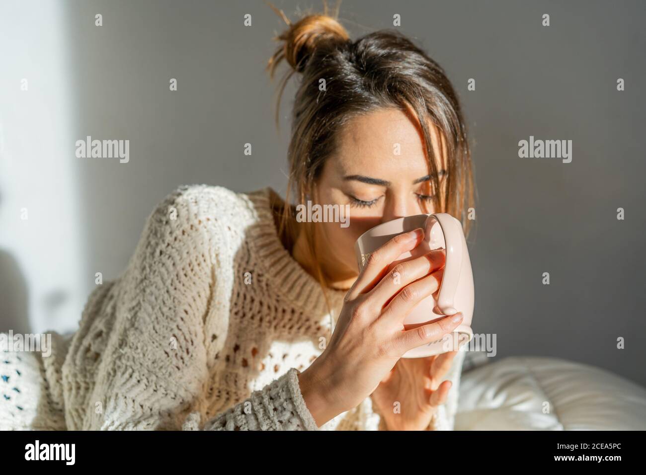 Woman with mug on bed Stock Photo