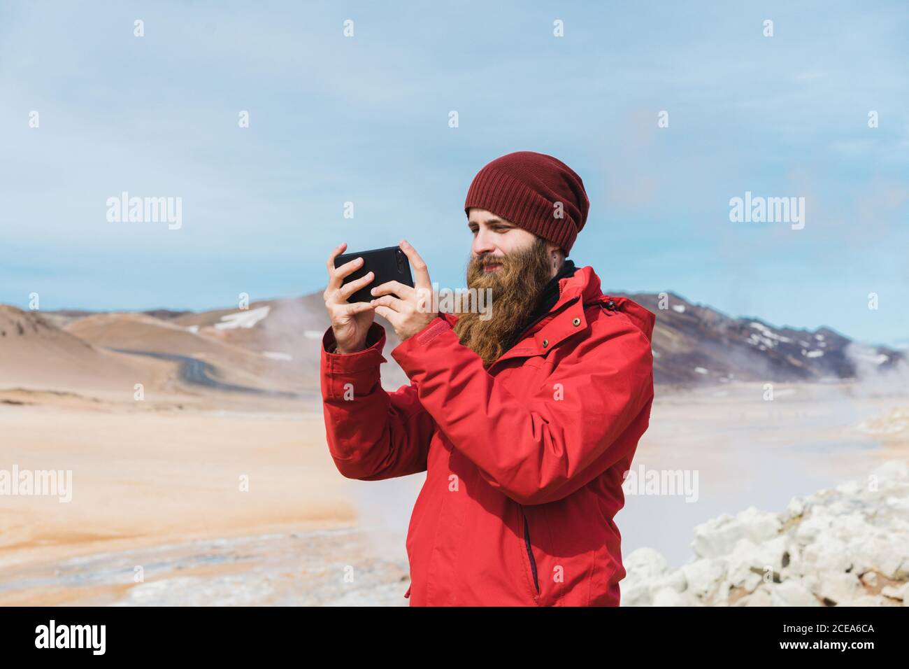 man standing with smartphone at geyser Stock Photo