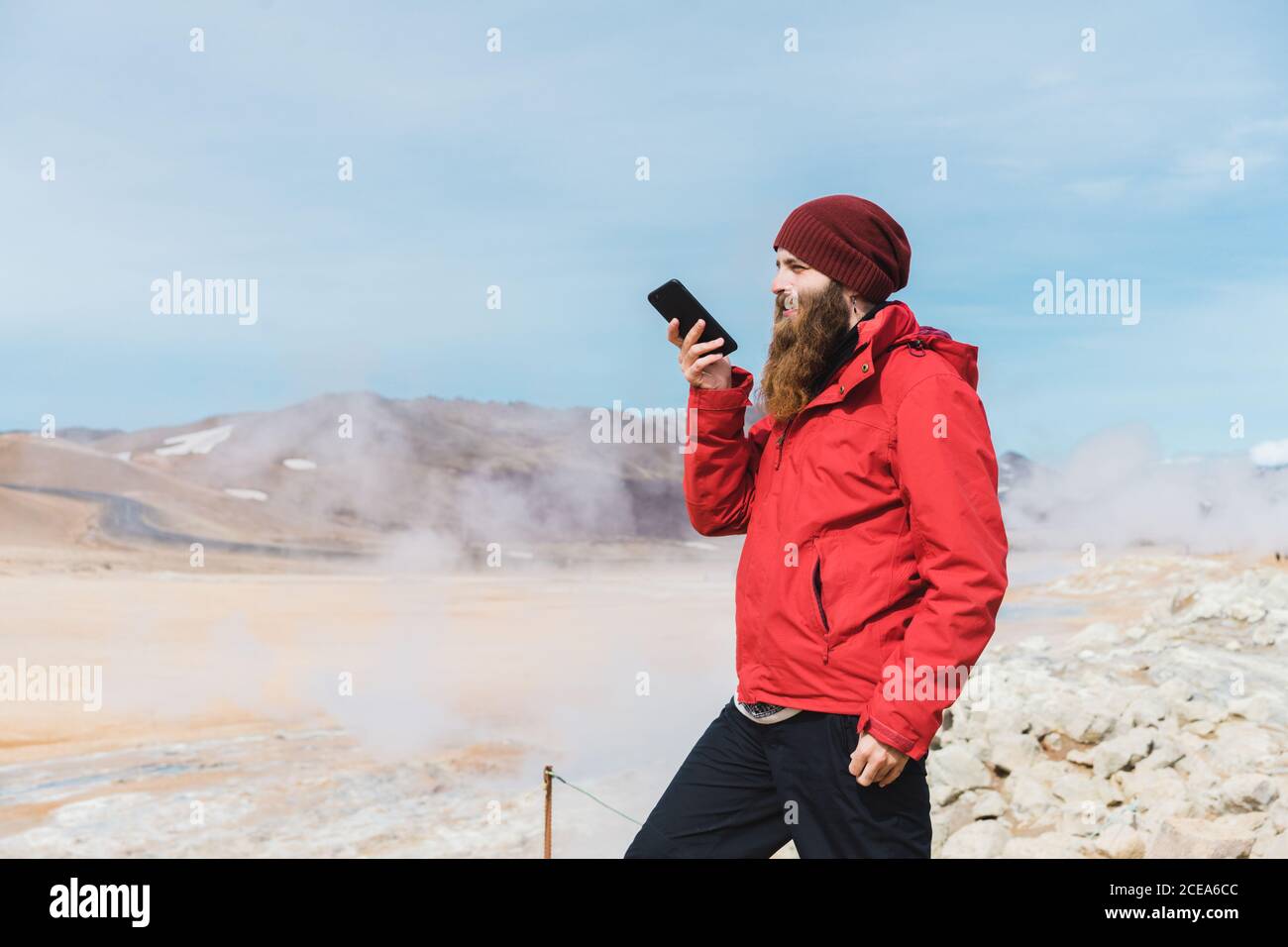 man standing with smartphone at geyser Stock Photo