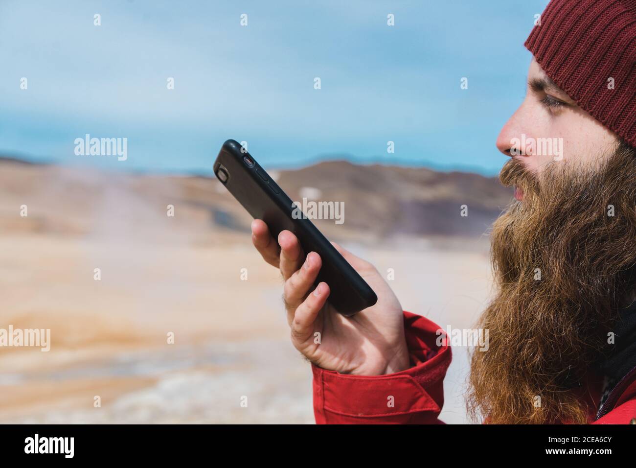 man standing with smartphone at geyser Stock Photo
