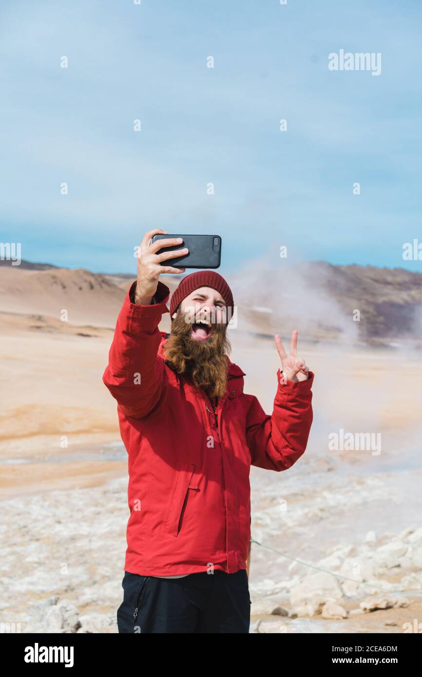 man standing with smartphone at geyser Stock Photo
