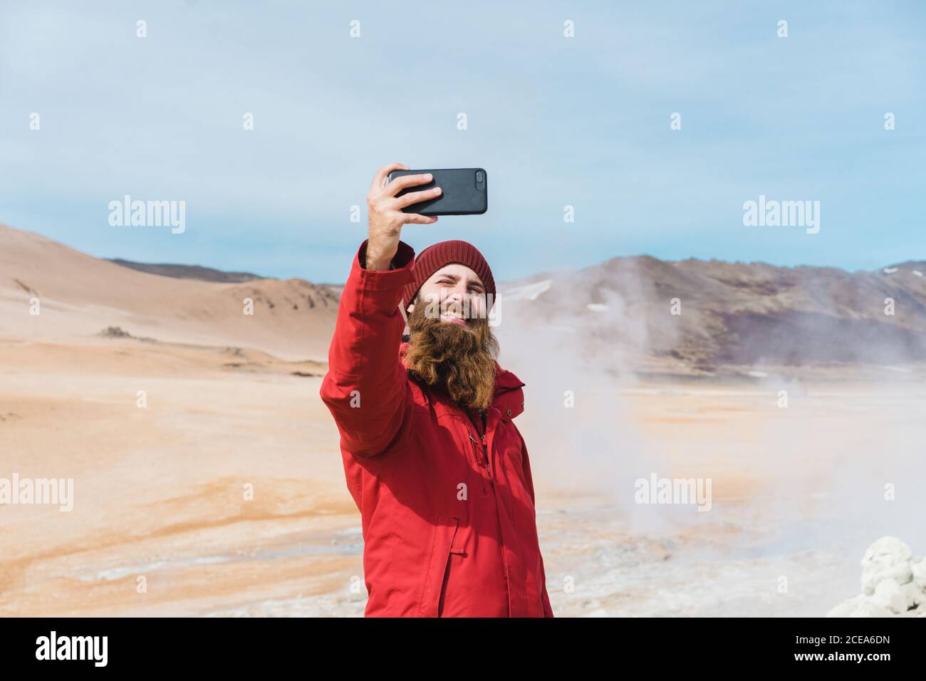 man standing with smartphone at geyser Stock Photo
