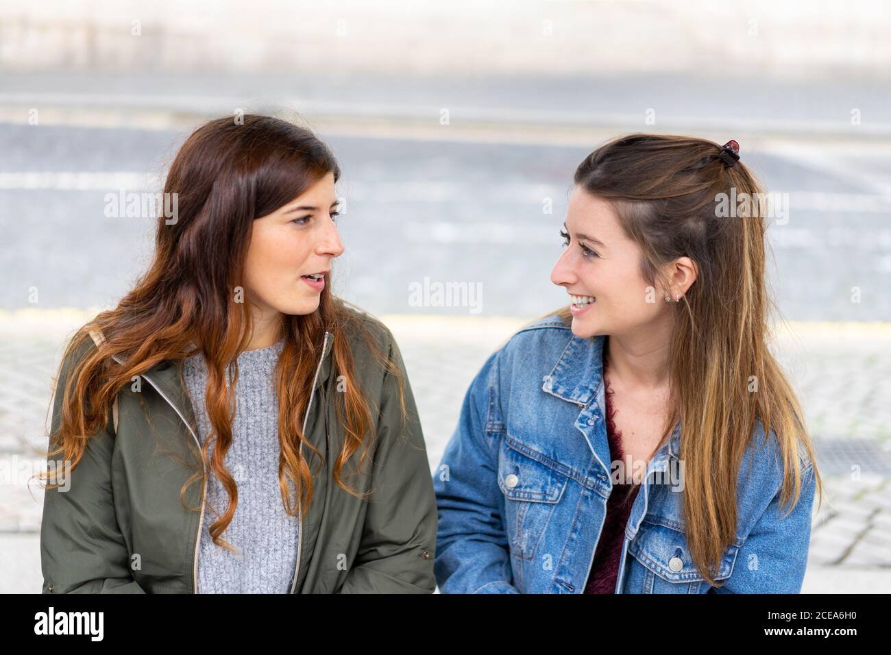 Young ladies in casual wear sitting on bench Stock Photo