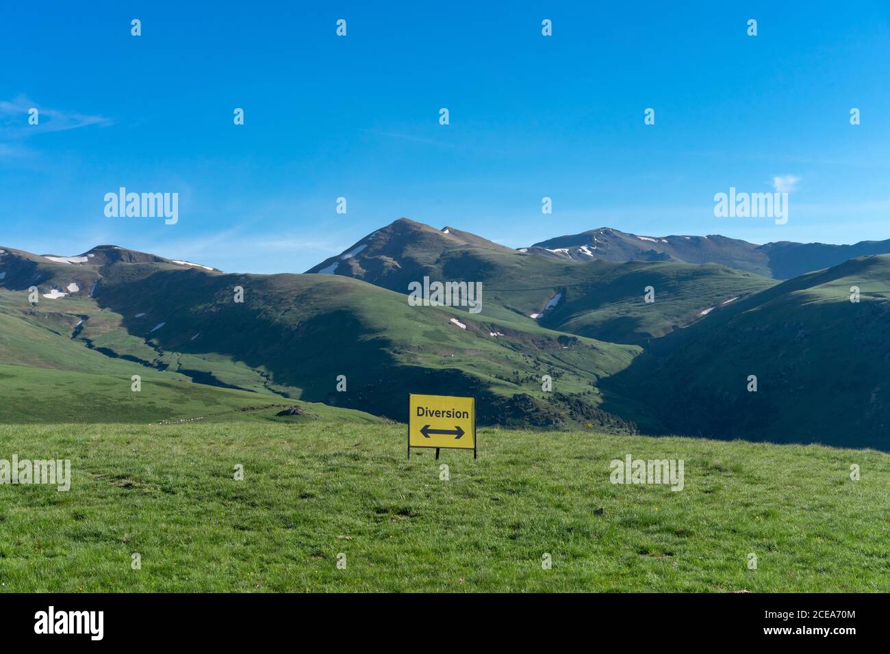 Green landscape of mountains and yellow sign showing diversion with