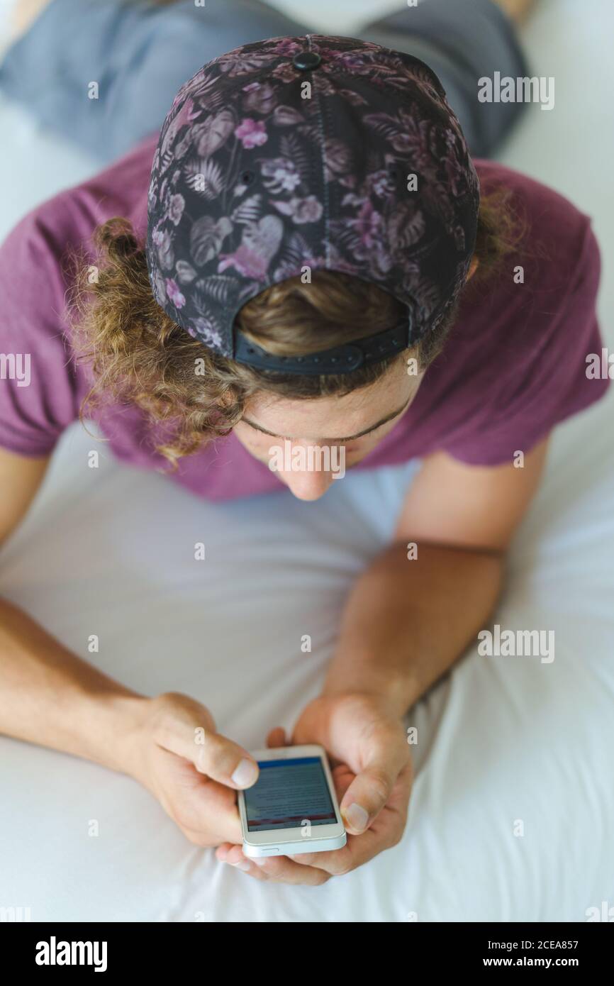 man using smartphone on bed Stock Photo