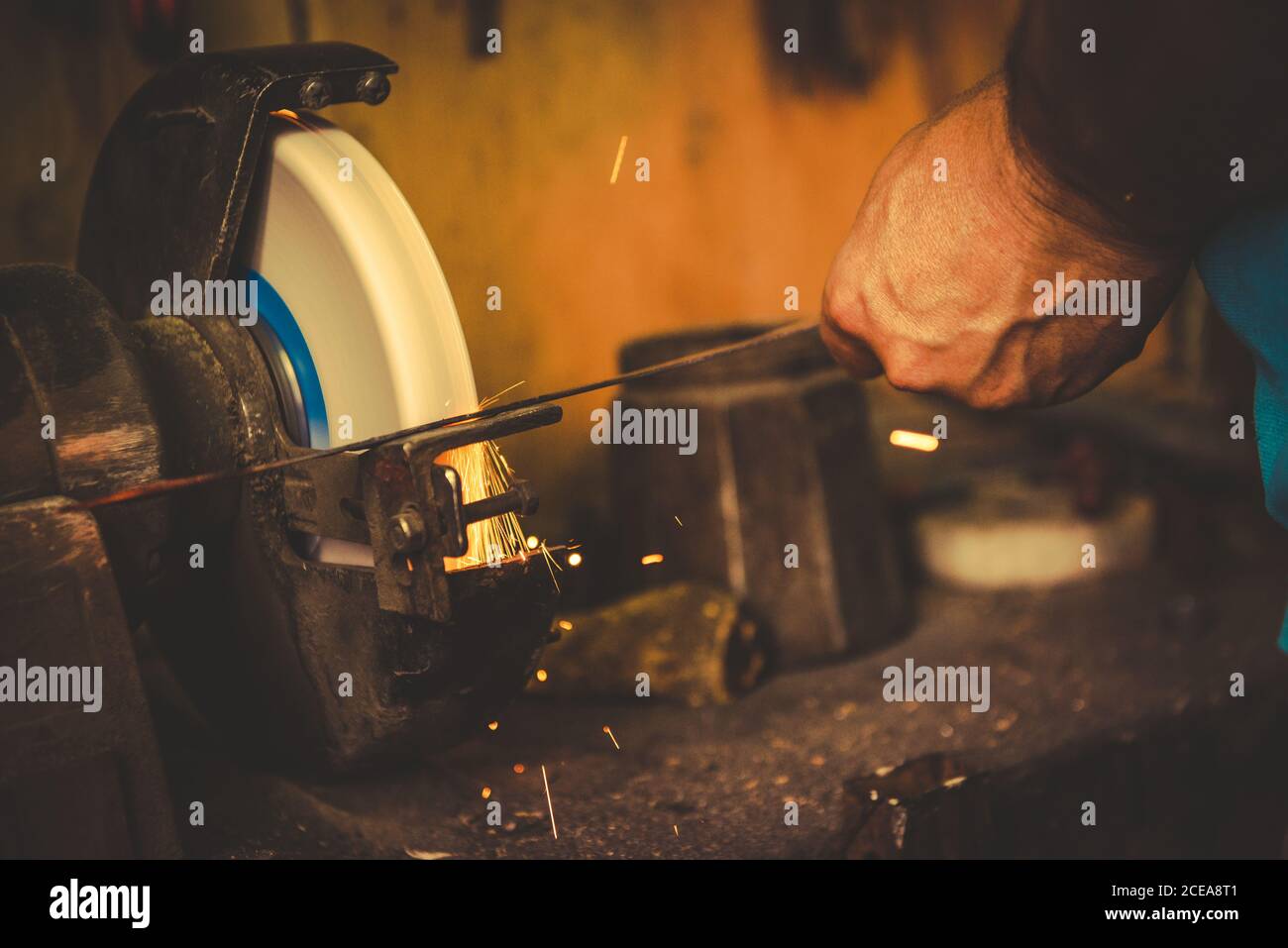 Crop smith using grindstone to sharpen metal blade in professional