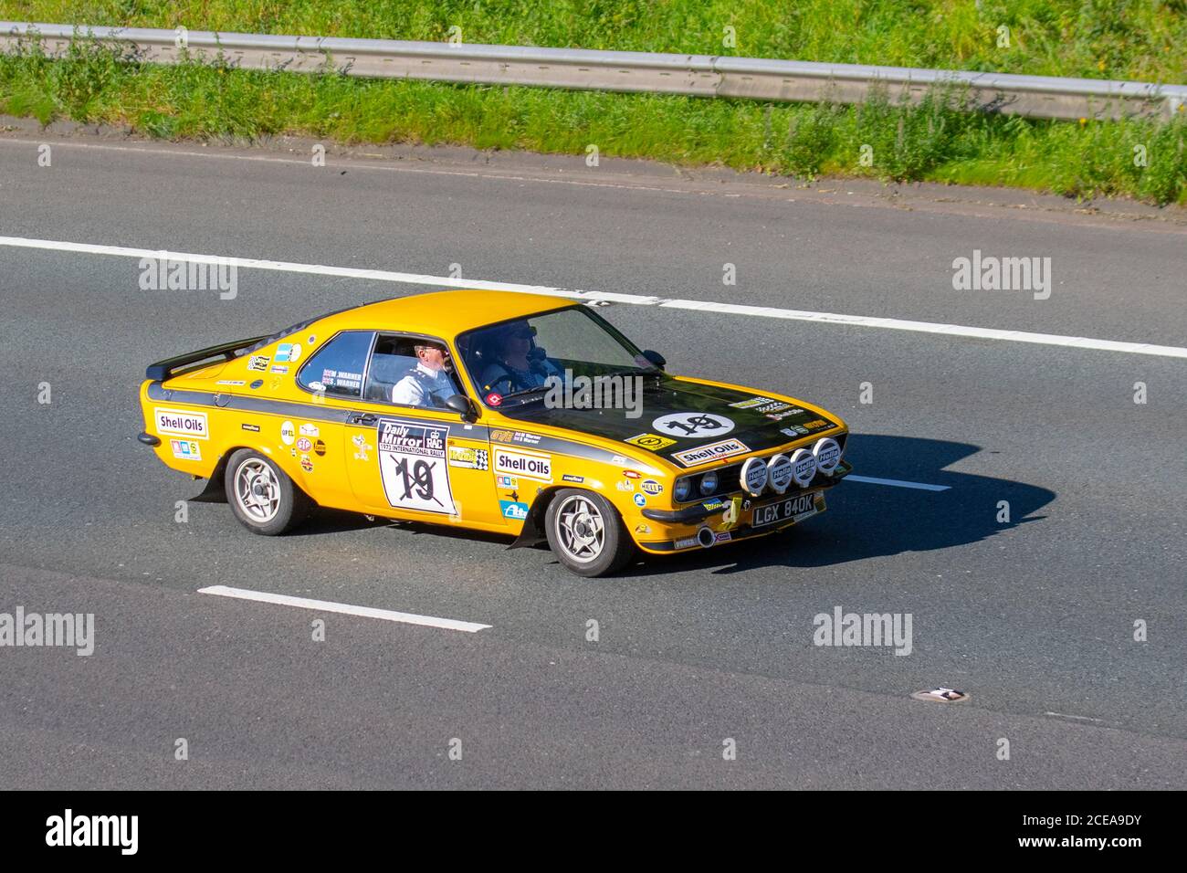 1992 70s seventies yellow Opel Manta motorsport No.19 1897cc petrol  sponsored racing car with motorsport decals; Vehicular traffic moving vehicles, cars driving vehicle on UK roads, motors, motoring on the M6 motorway highway network. Stock Photo