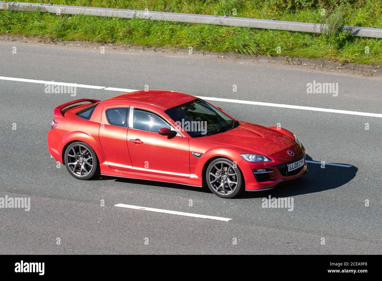 2009 red Mazda RX8 R3; Vehicular traffic moving vehicles, cars driving vehicle on UK roads, motors, motoring on the M6 motorway highway network. Stock Photo