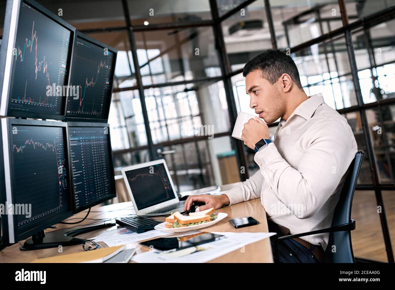 Stock Traiding. Trader sitting at office in front of monitors with data  using trading bot make trades cryptocurrency exchange while having  breakfast Stock Photo - Alamy