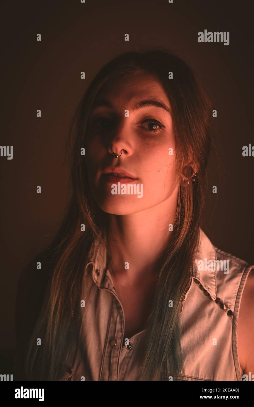 Charming young lady with piercing looking at camera in brown background Stock Photo