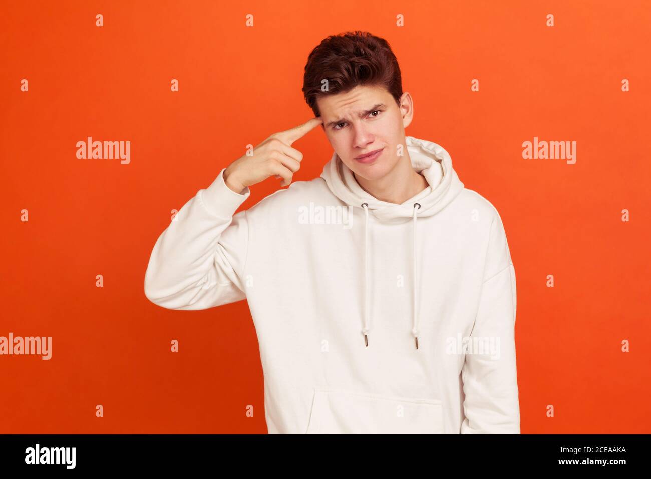 Unhappy frustrated young man in white hoodie and stylish hairdo showing stupid gesture, does not believe in his strengths, capabilities, disappointed. Stock Photo